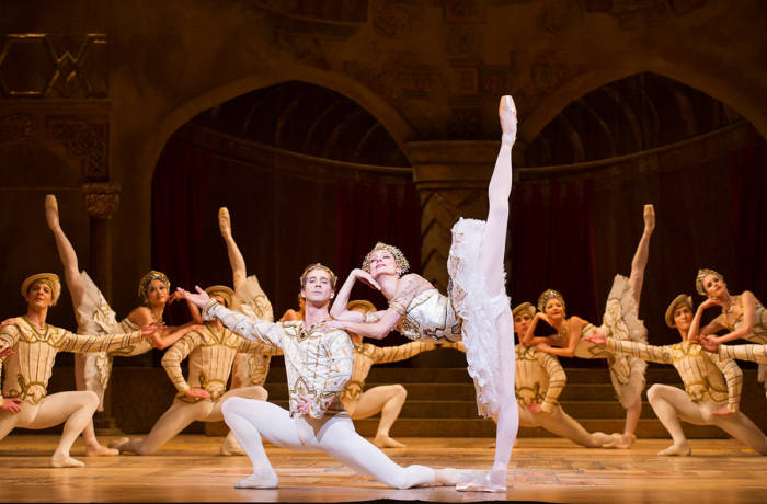 A ballet performance with people dressed in white and gold