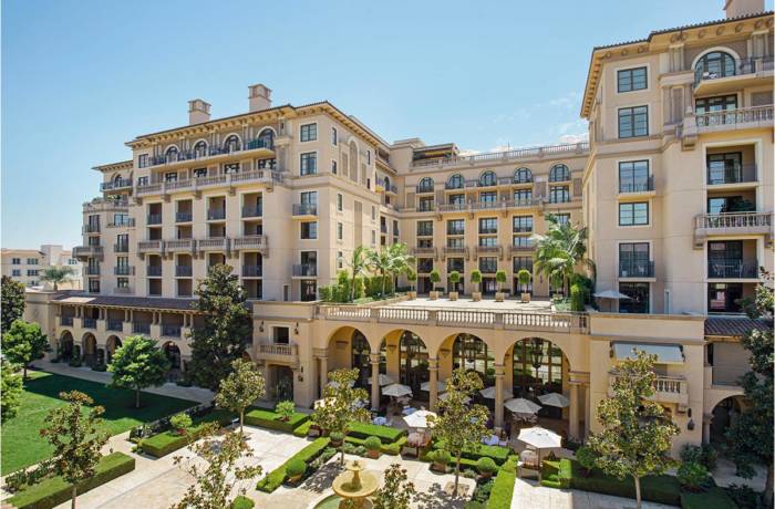 the entrance of a hotel with arched windows and doors and plants