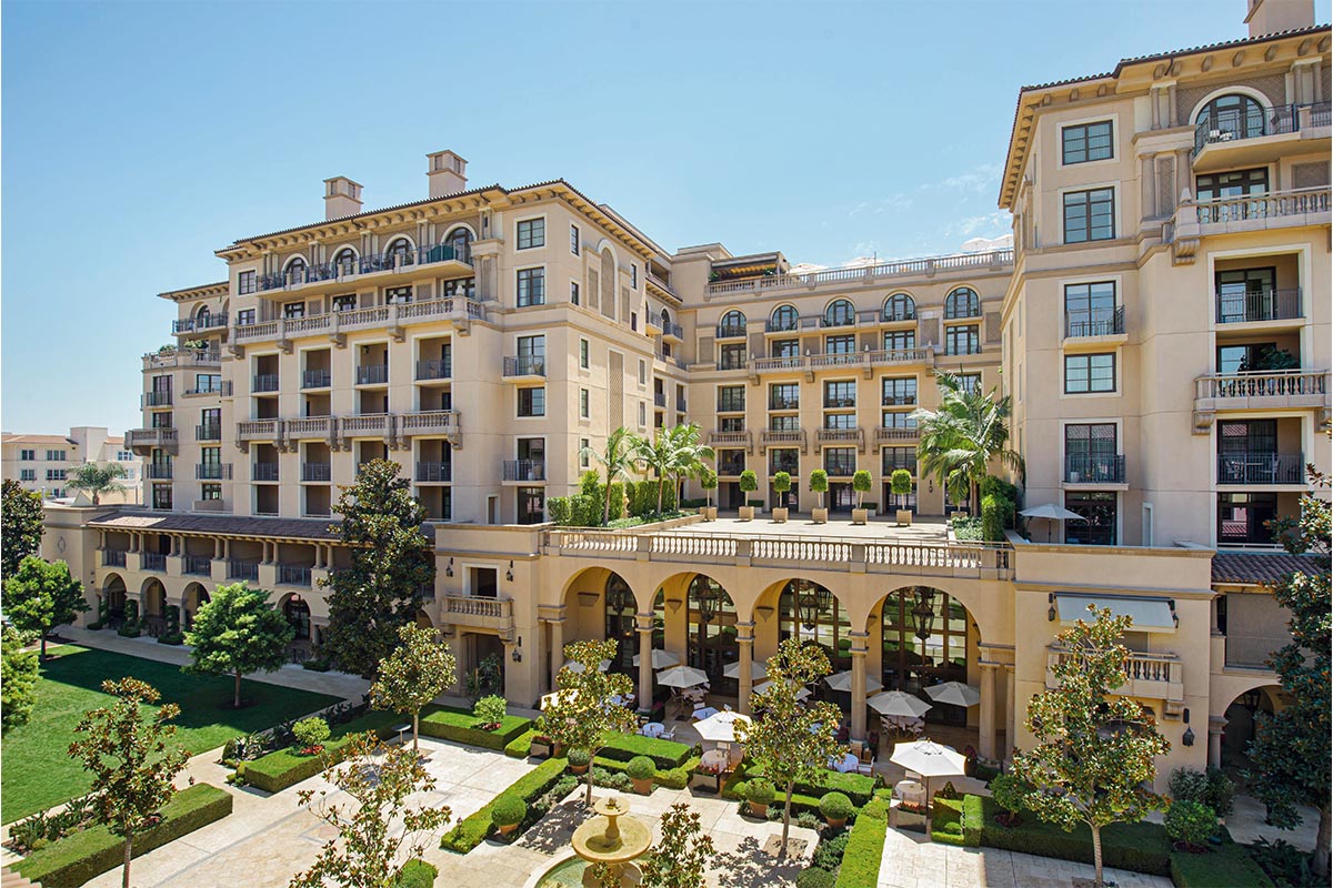 the entrance of a hotel with arched windows and doors and plants