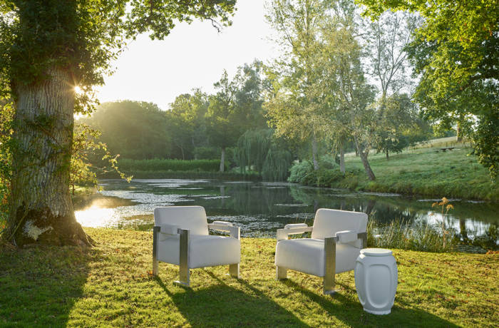 white chairs on the grass by a pond