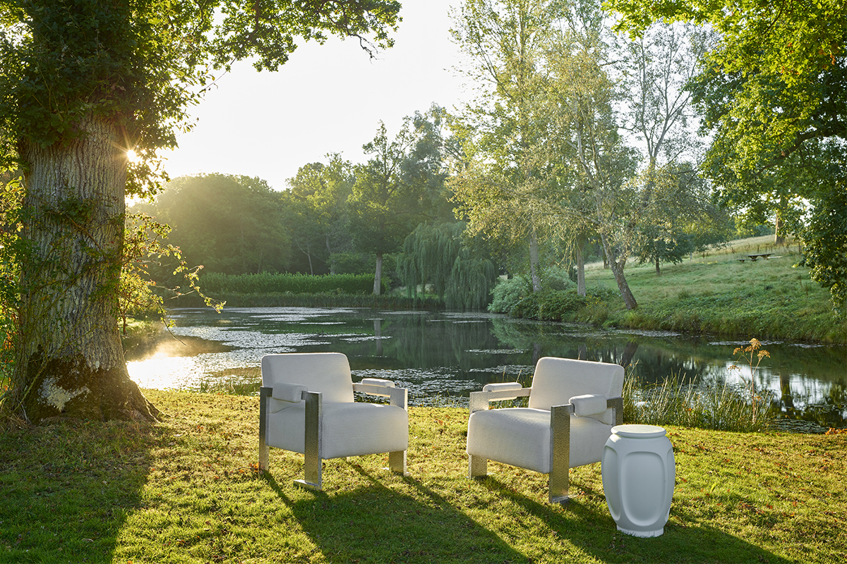 white chairs on the grass by a pond