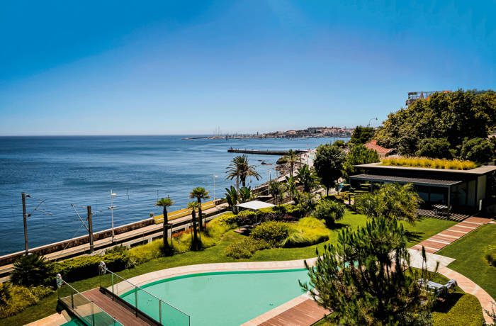 a swimming pool by the sea surrounded by grass and trees