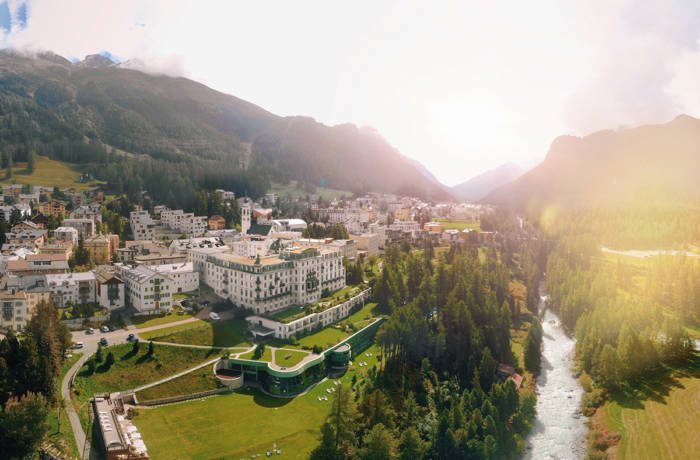 A palace surrounded by green grass, a river and mountains