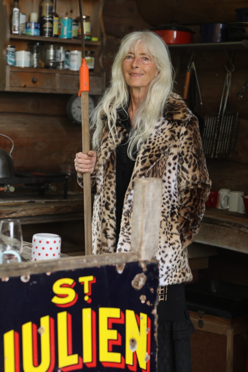 A blonde woman in a leopard print coat holding a stick