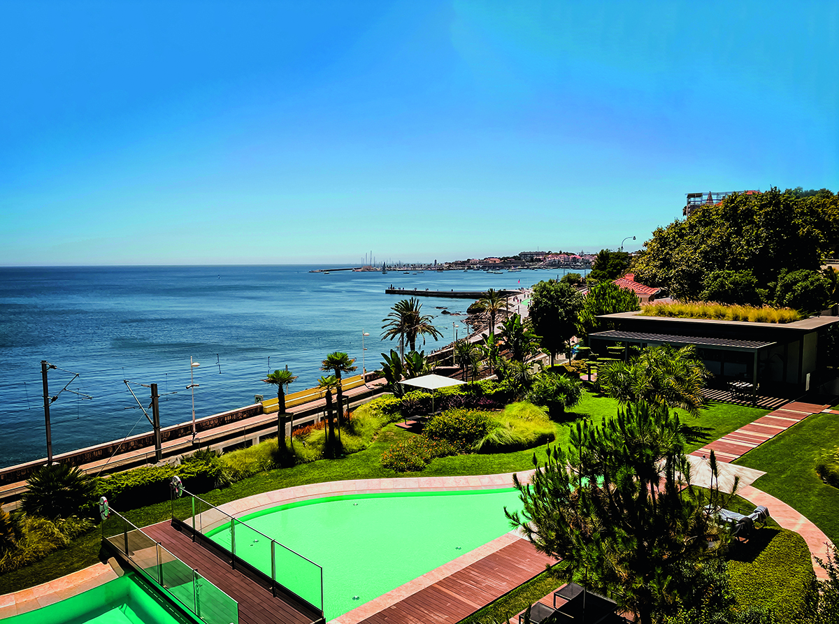 a swimming pool by the sea surrounded by grass and trees