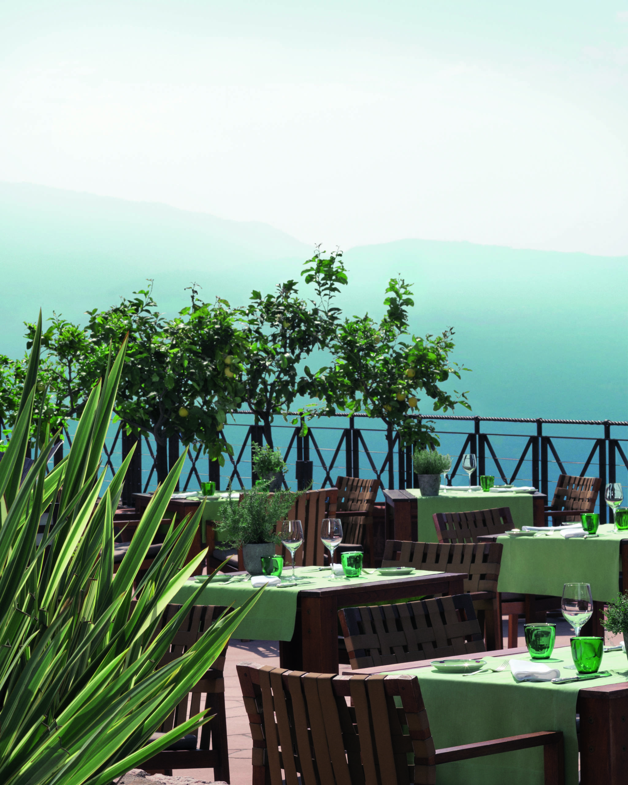 restaurant on a terrace with green tablecloths and a view of the mountains and lake