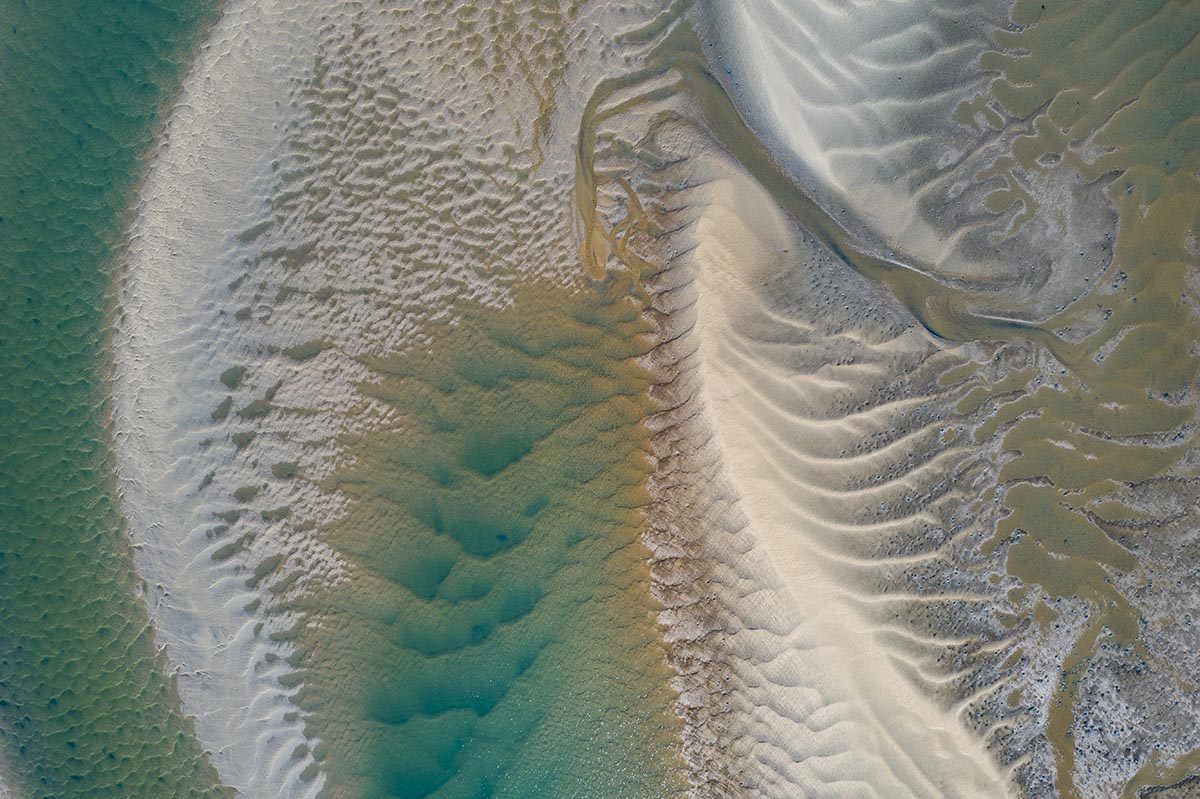 the blue sea from a satellite view with sand that looks like waves