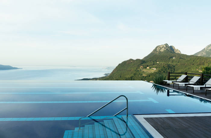 An infinity pool overlooking a lake and green mountain