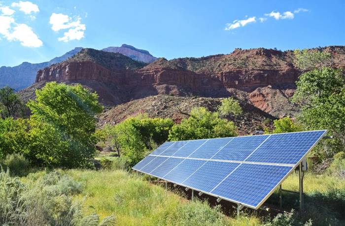 solar panel on the grass with rocky mountains behind it