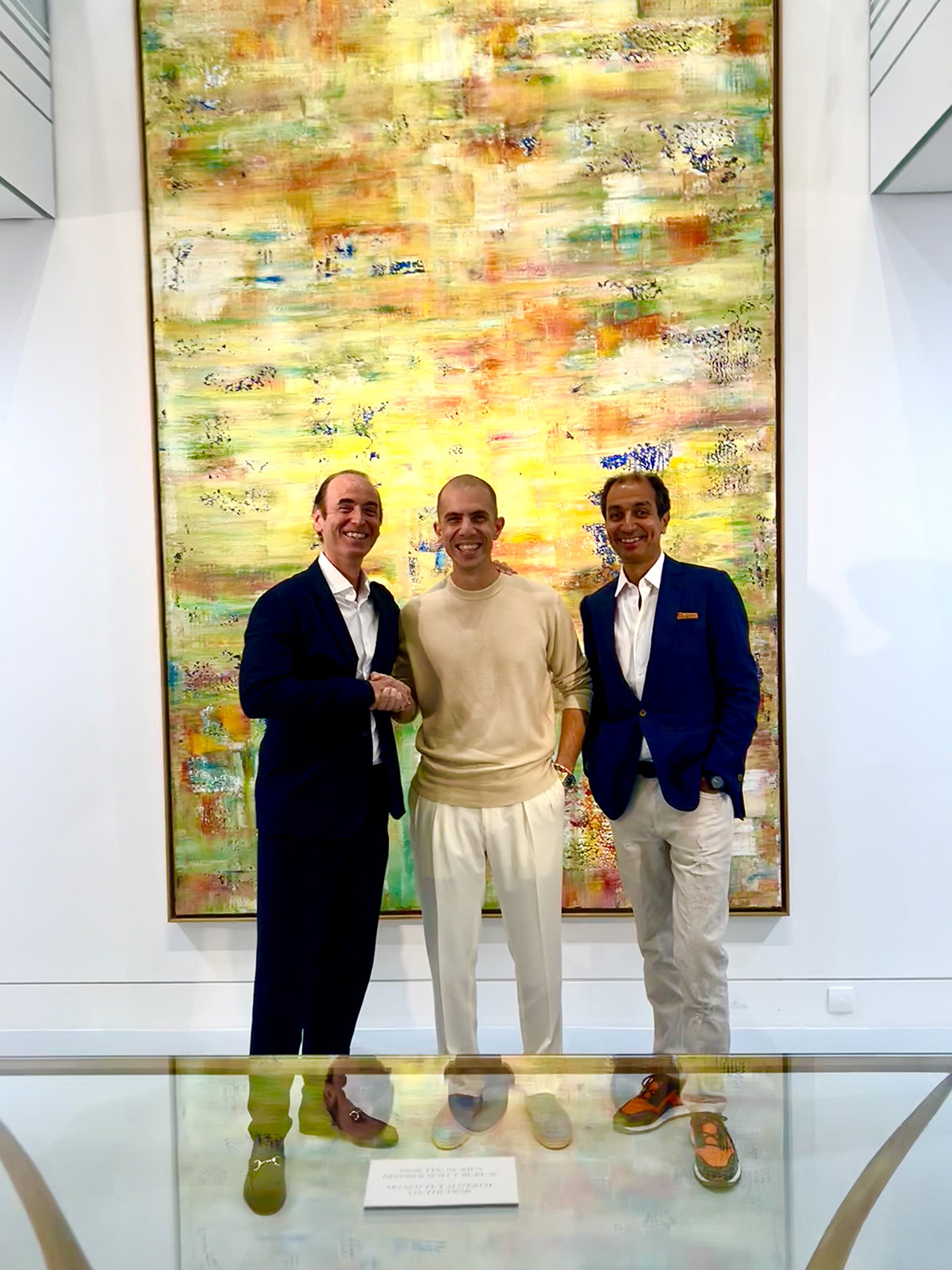 three men standing in front of a yellow painting
