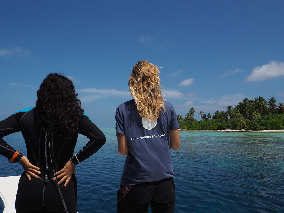 two girls on a boat on the sea wearing wet suits