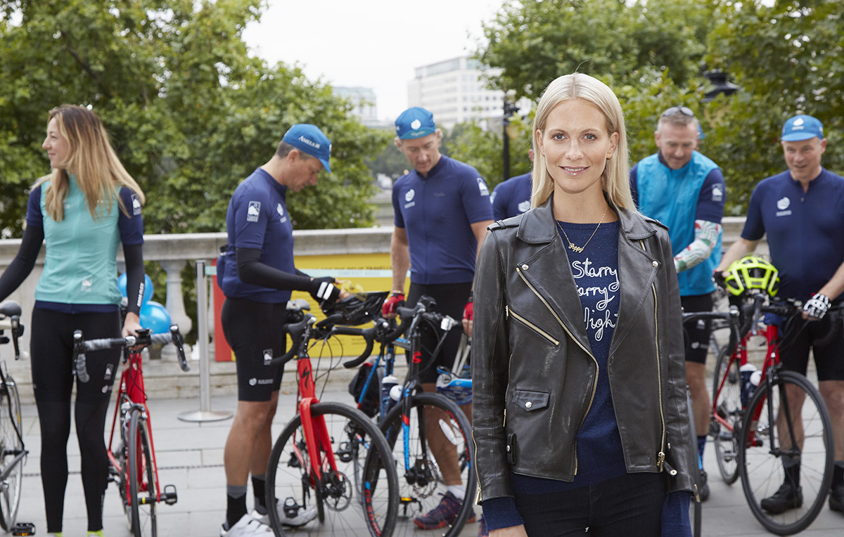 Poppy Delevigne standing in front of a group of cyclists