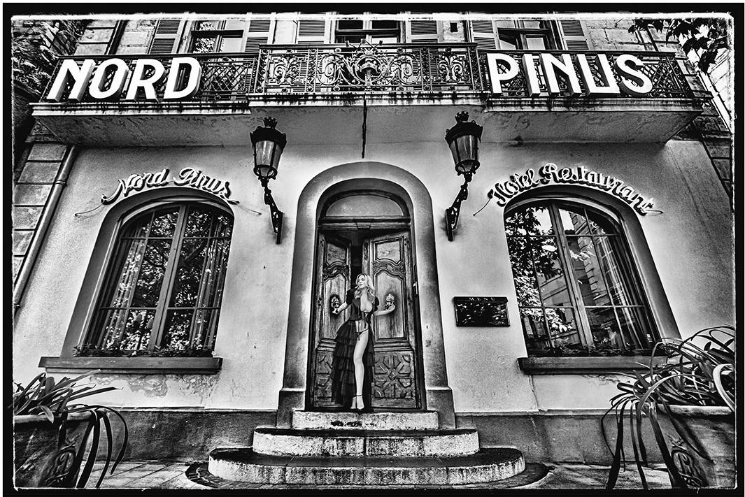 The front of a hotel with a woman coming out of it and a sign that says Nord Pinus