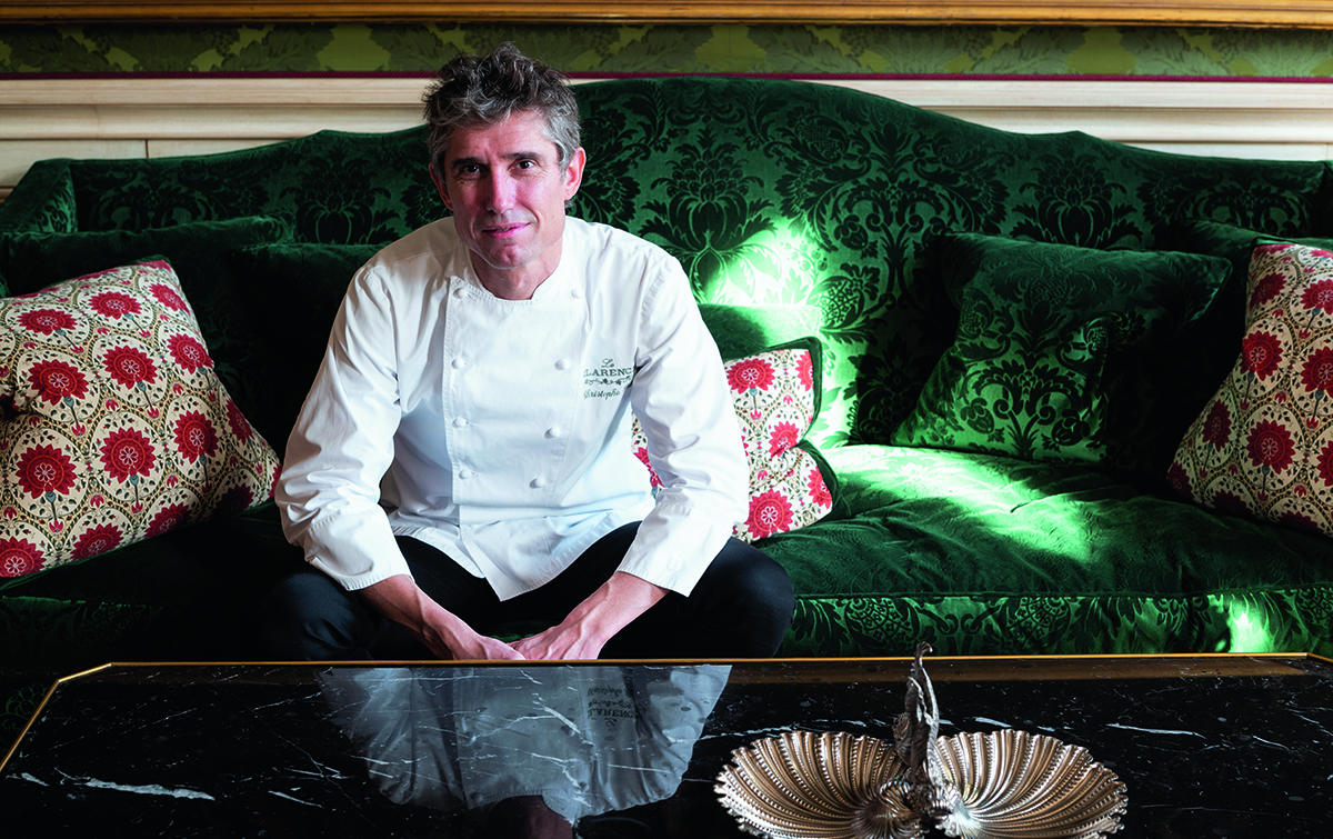 A chef sitting in his apron on a green couch