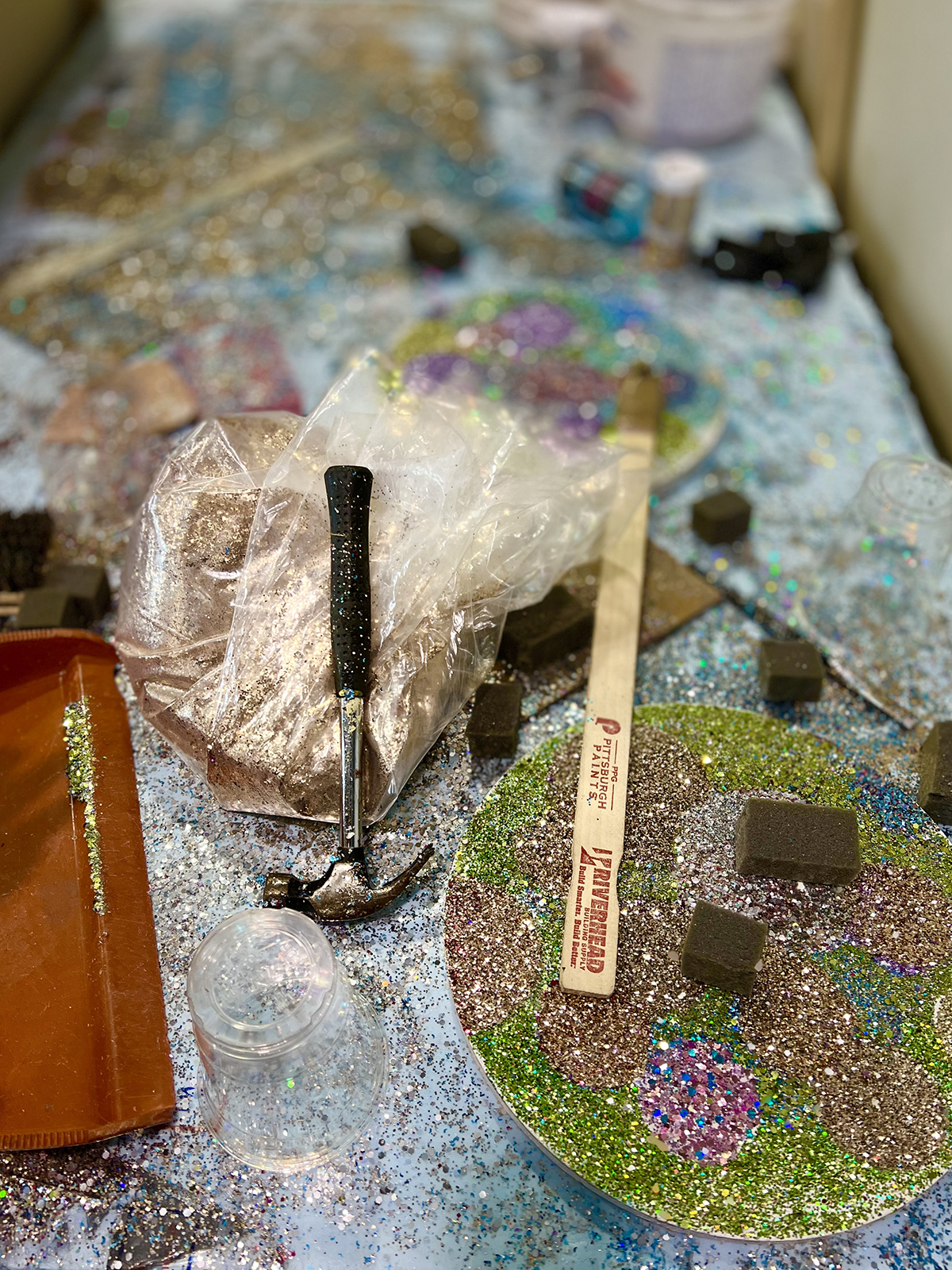 A paint brush and scalpel on a table covered in glitter