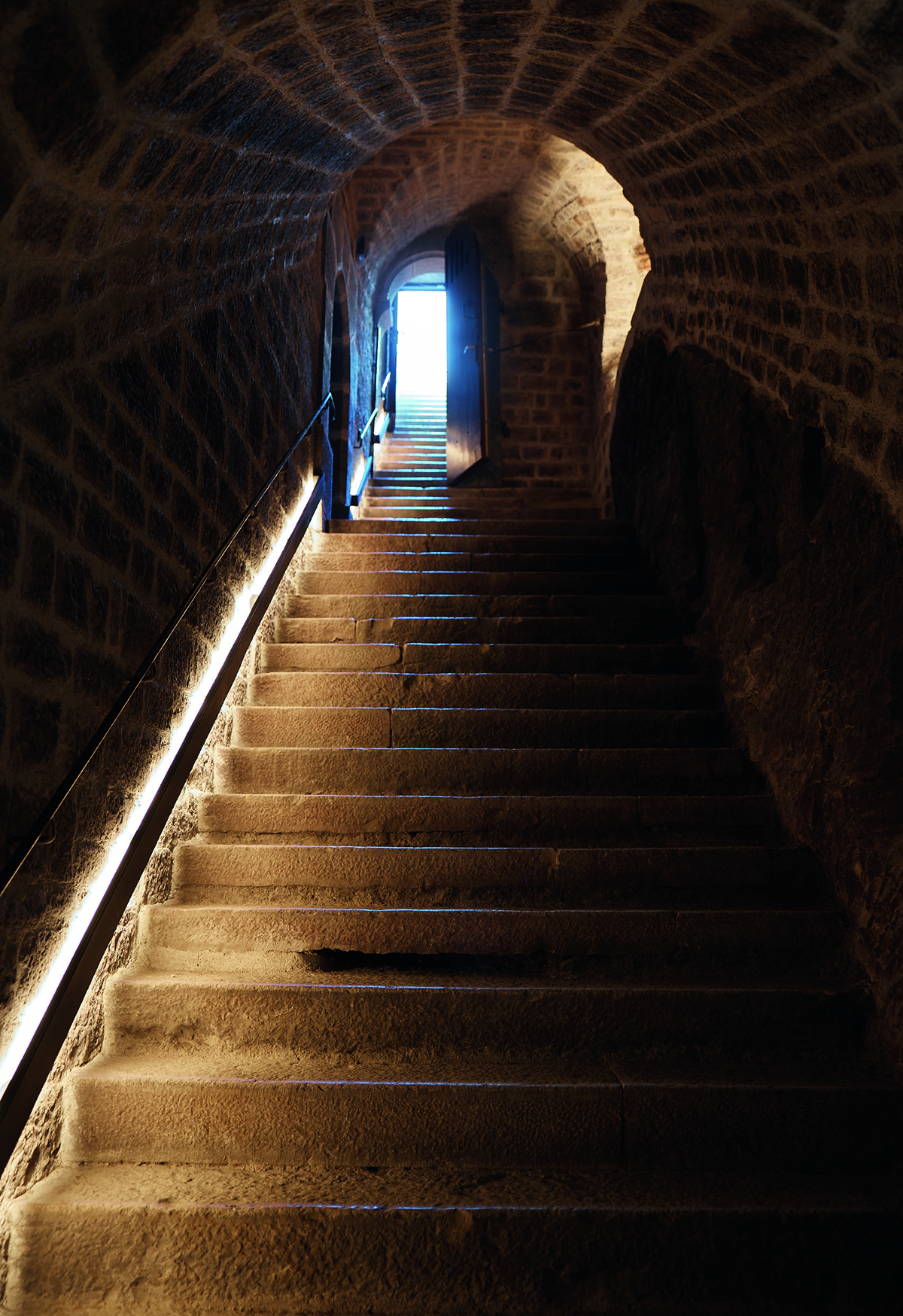 stone steps and brick walls lit up leading to an arched door