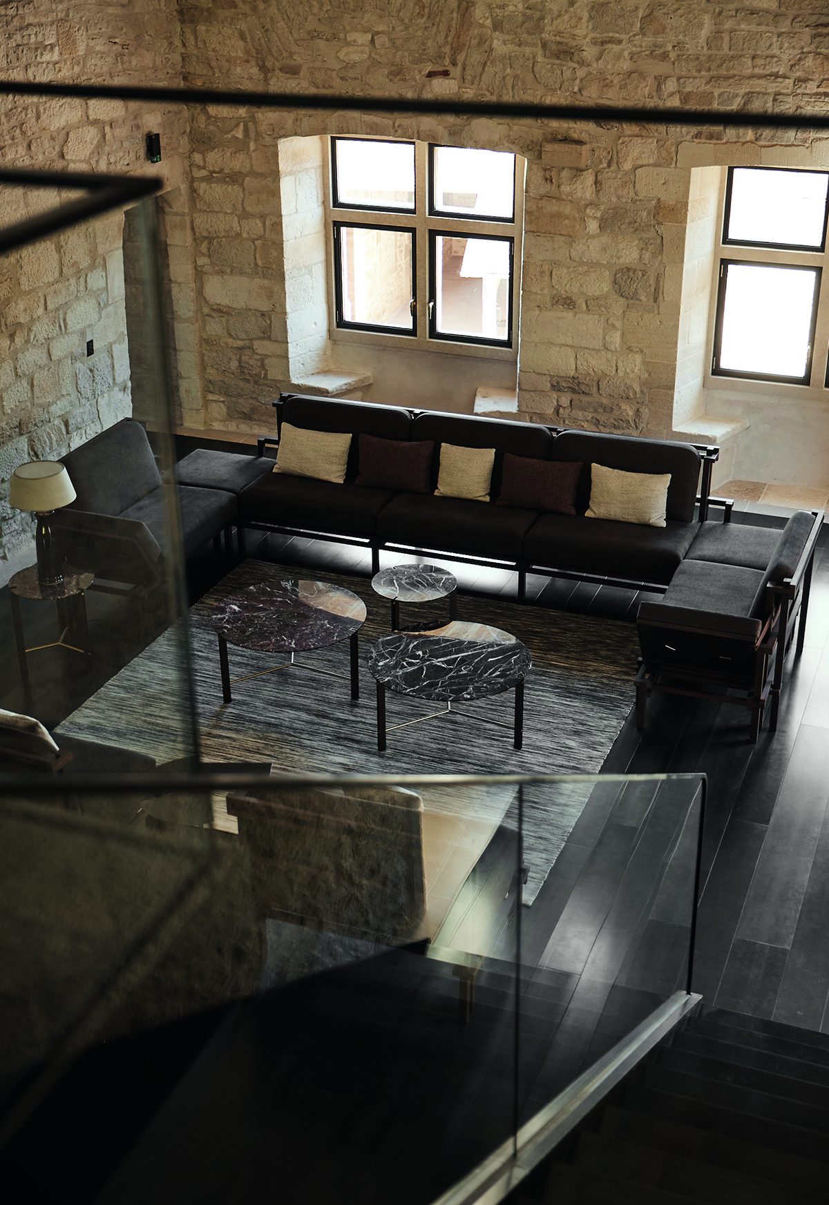 brown sofas and a coffee table in a glass and stone room