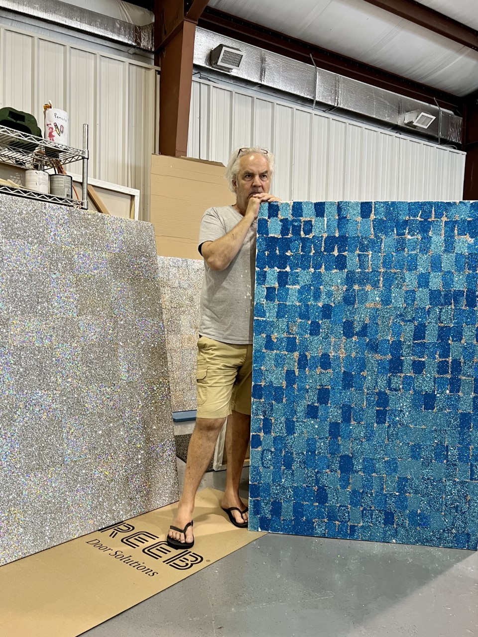 A man standing by a large canvas of blue squares