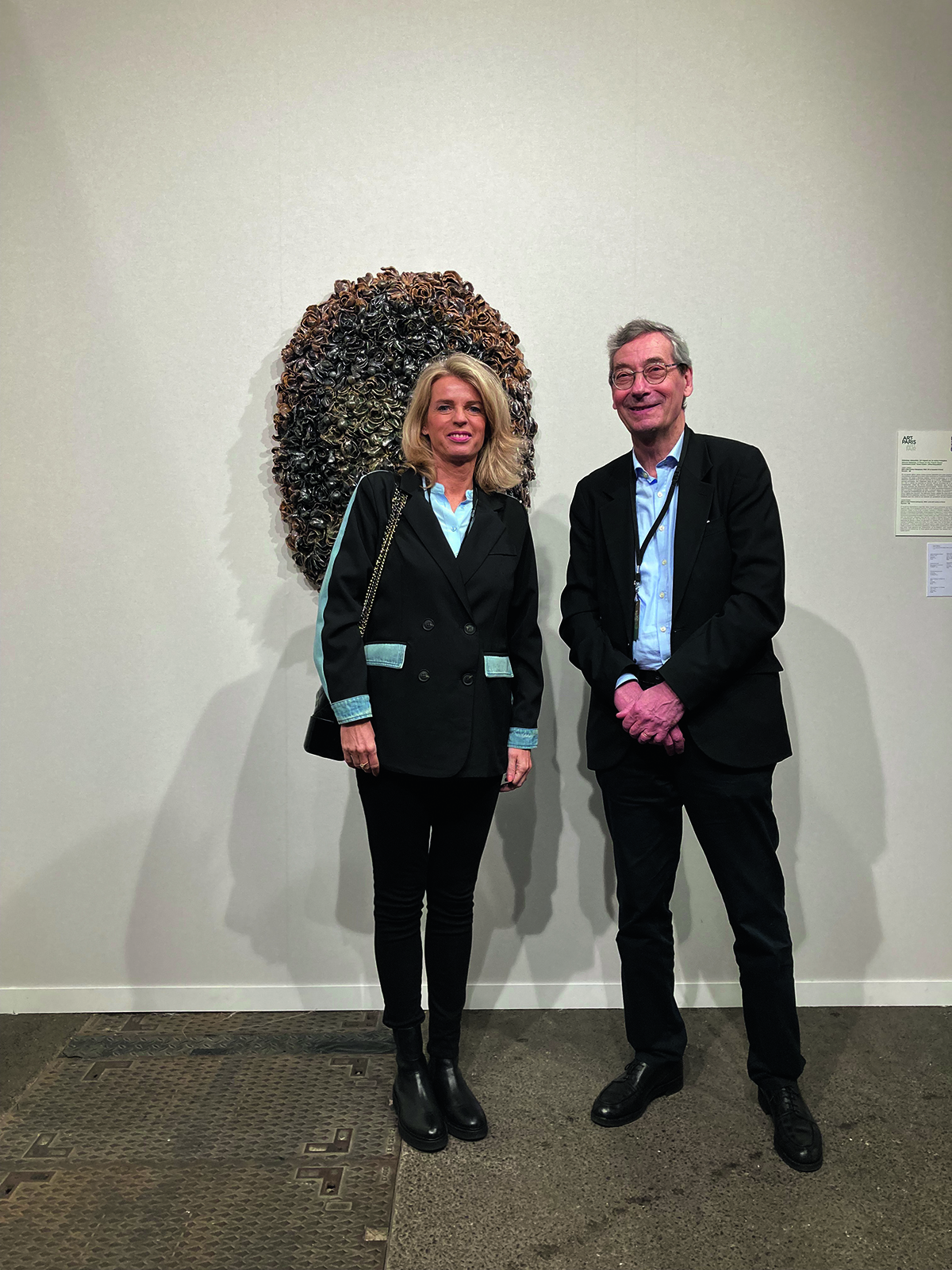 A woman and man standing in front of a piece of art on the wall