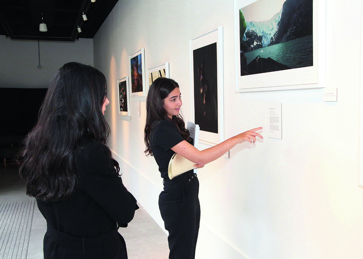 A woman in a black jumpsuit showing another woman an artwork