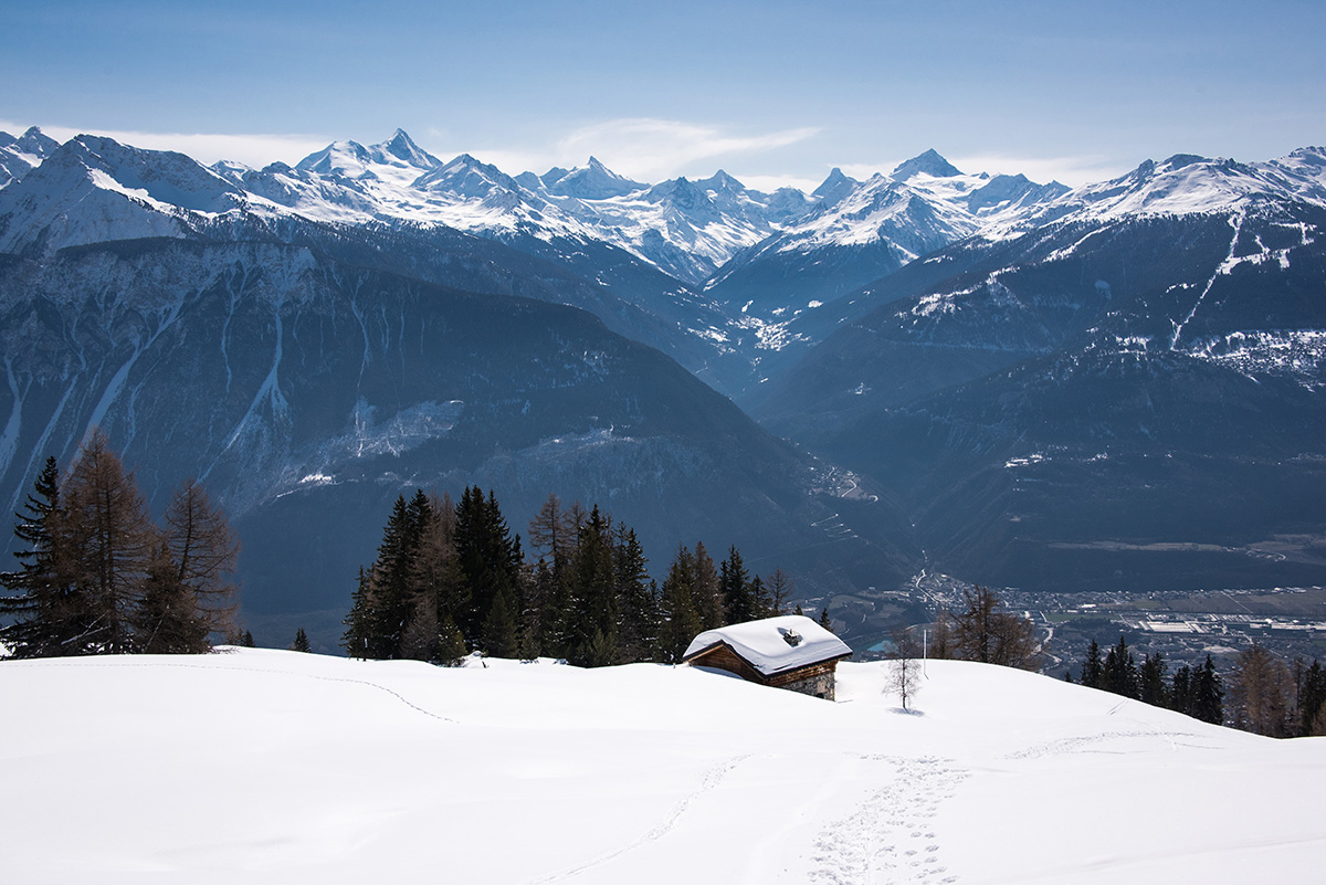 a small hut on a mountain covered in snow and trees around it