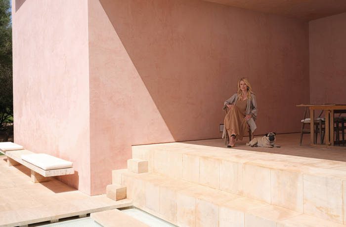 A woman sitting with a pug in a pink stone terrace house