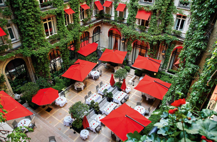 Hotel courtyard with leaves and red umbrellas and awnings