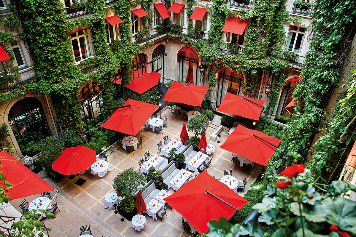 Hotel courtyard with leaves and red umbrellas and awnings