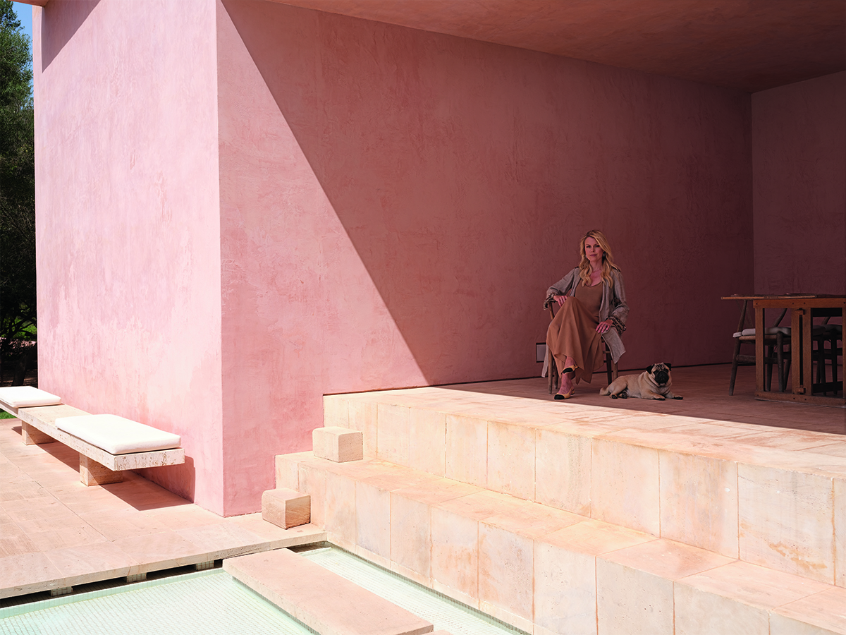 A woman sitting with a pug in a pink stone terrace house