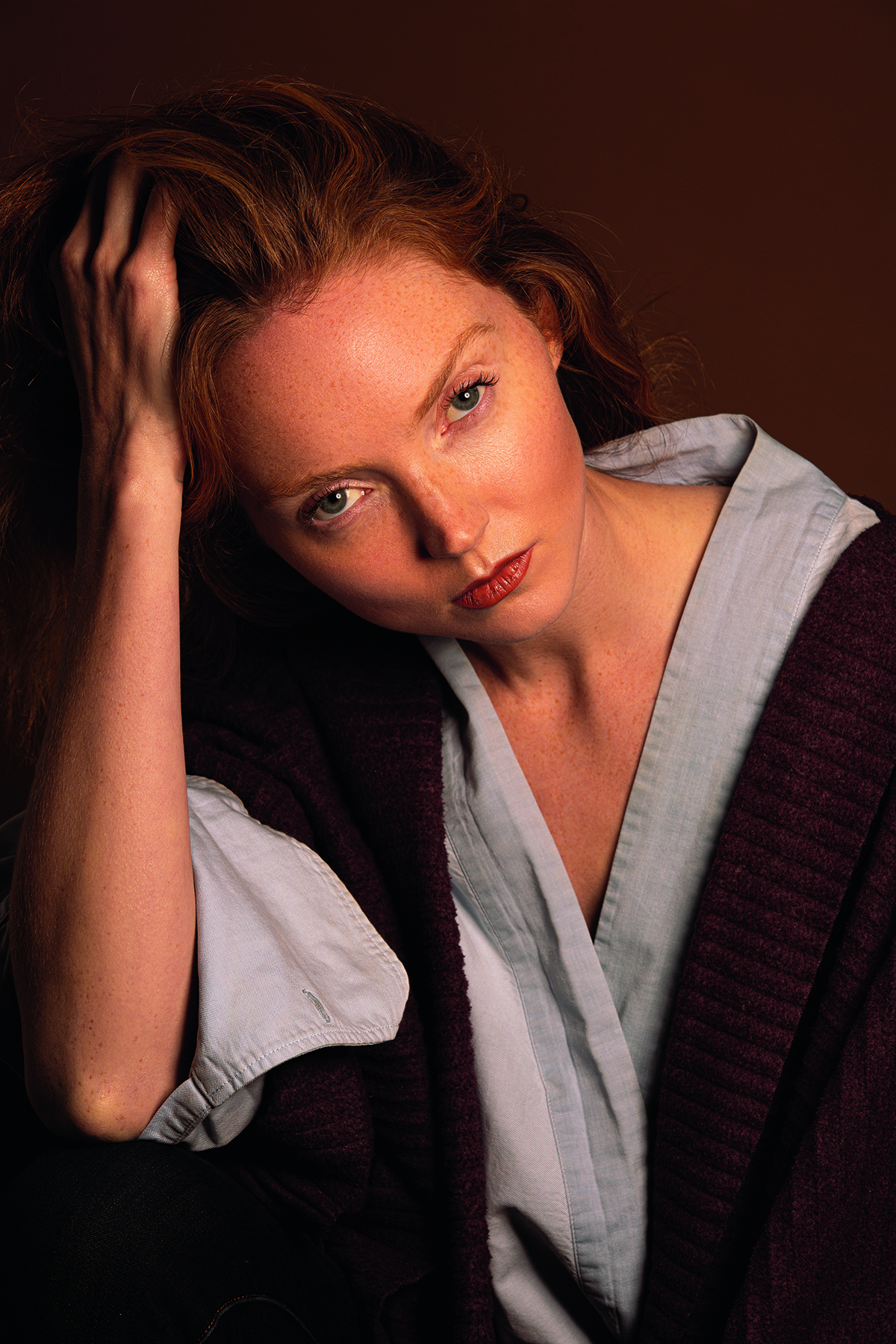 A ginger model wearing a brown and grey robe with her hand on her head