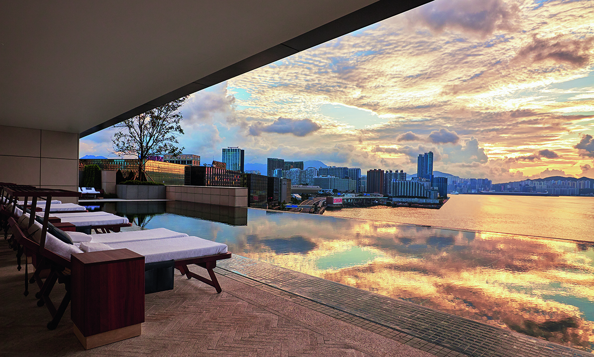 deck chairs and a pool on a roof terrace looking over the city of Hong Kong