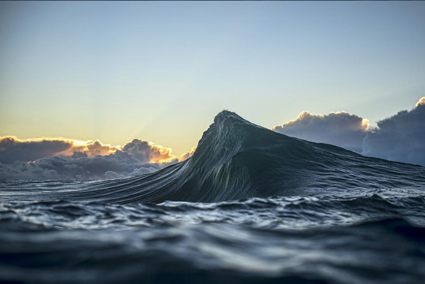 A wave in the sea and clouds above it