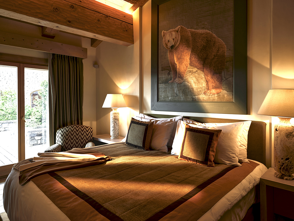 A bed with a picture of bear above it and a brown throw and cusions
