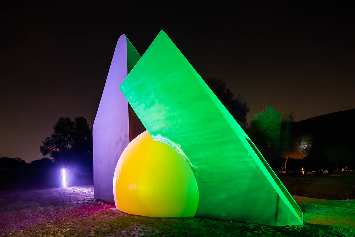 A green purple and yellow sculpture lit up in the dark