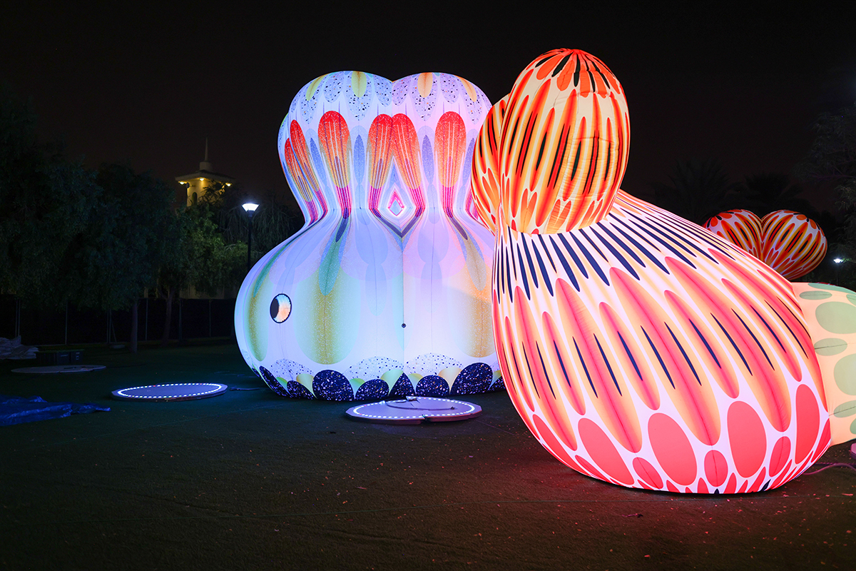 A pink and blue cartoon sculpture figure lit up in the dark