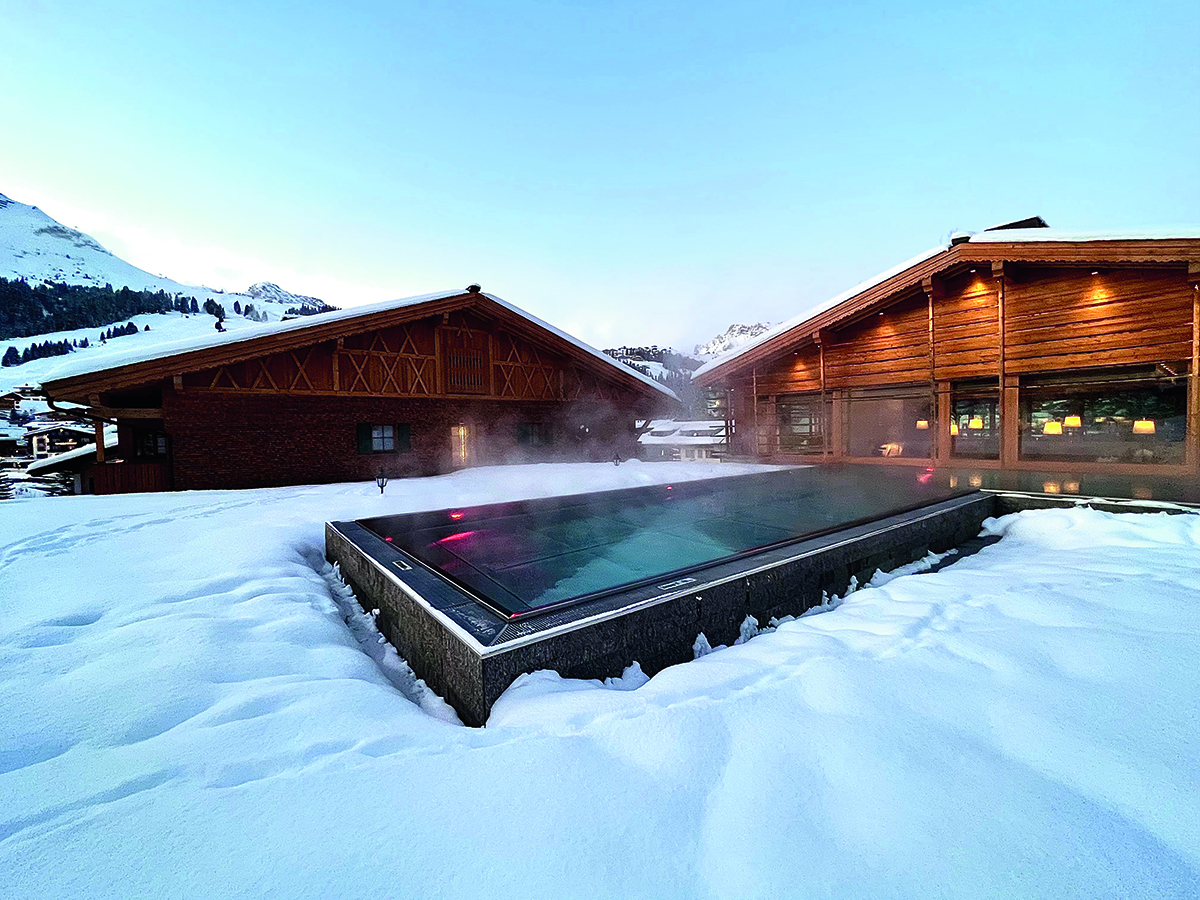 outdoor pool with snow around it and wooden houses in background