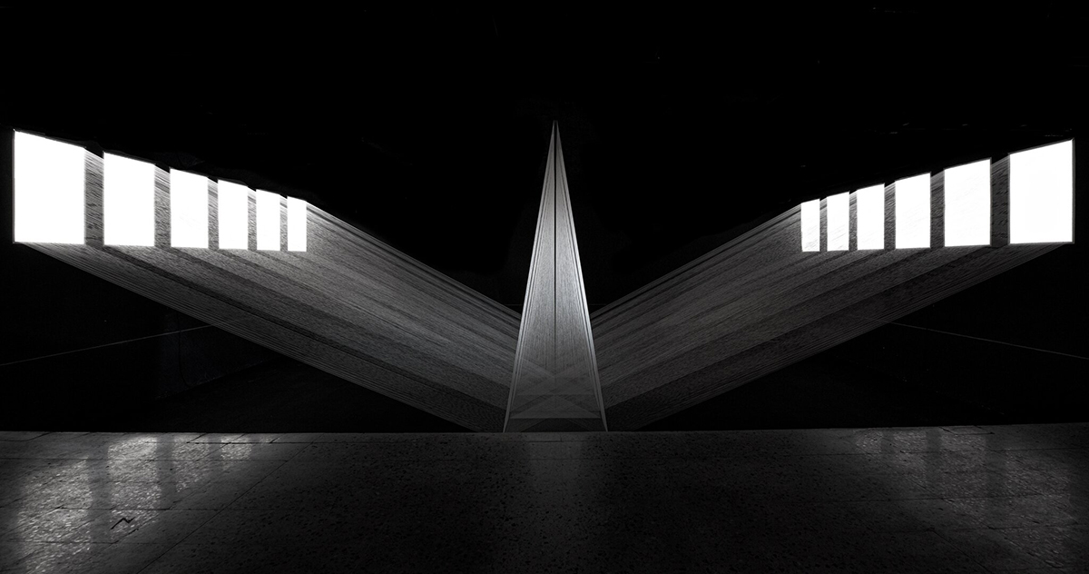 A silver light pyramid with lights shining through white squares in the dark