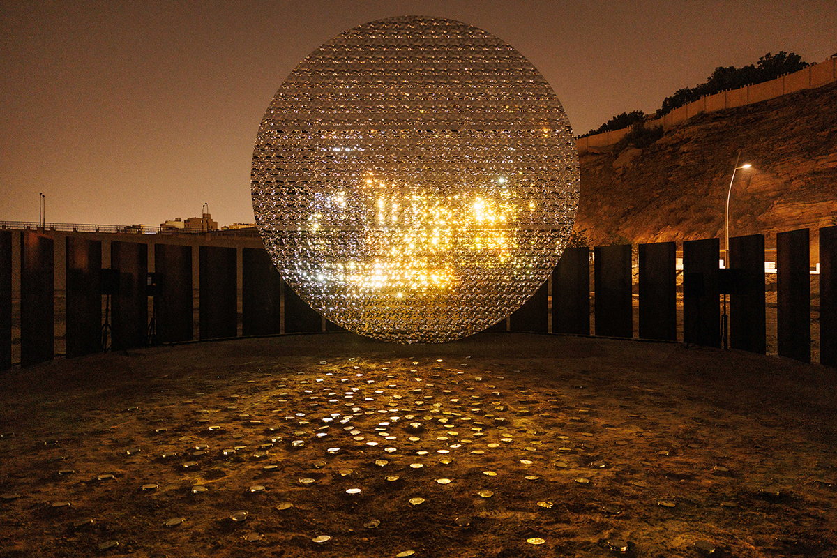 A huge disco-ball with yellow lights on it outdoors