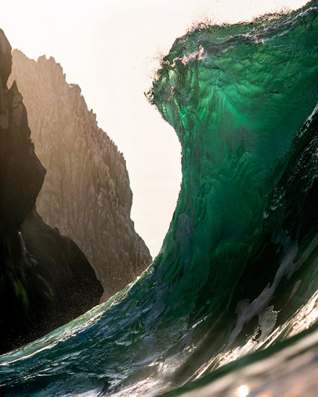 A huge wave and a mountain cliff beside it 