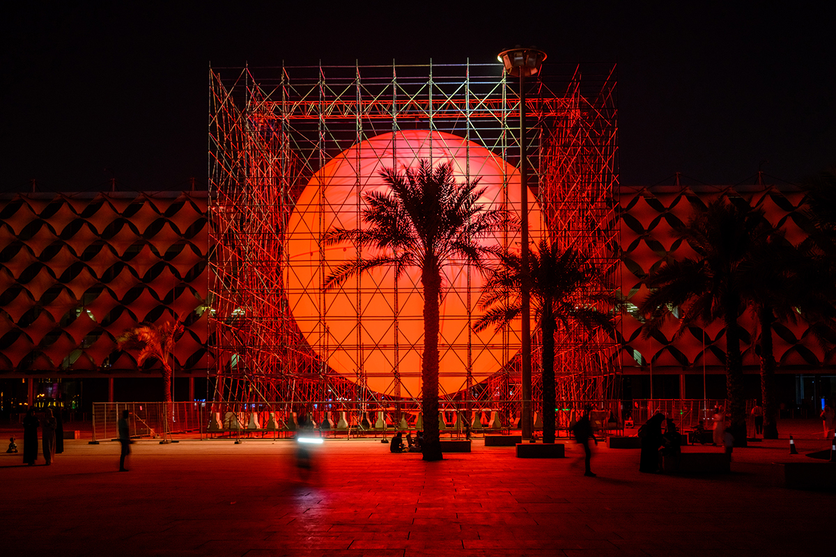 Palm trees in front of a red circle surrounded by scaffolding