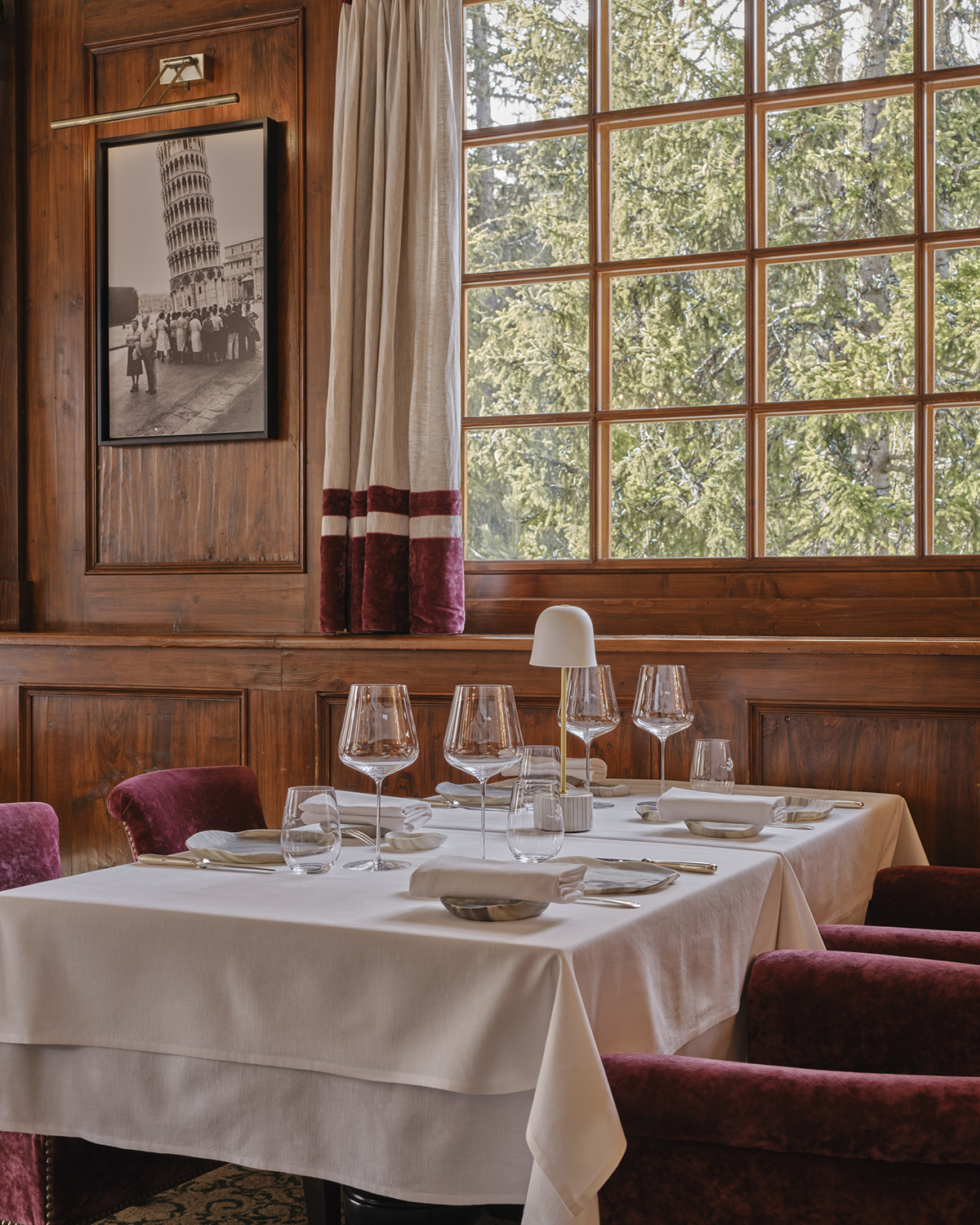 A table by a window with red velvet chairs