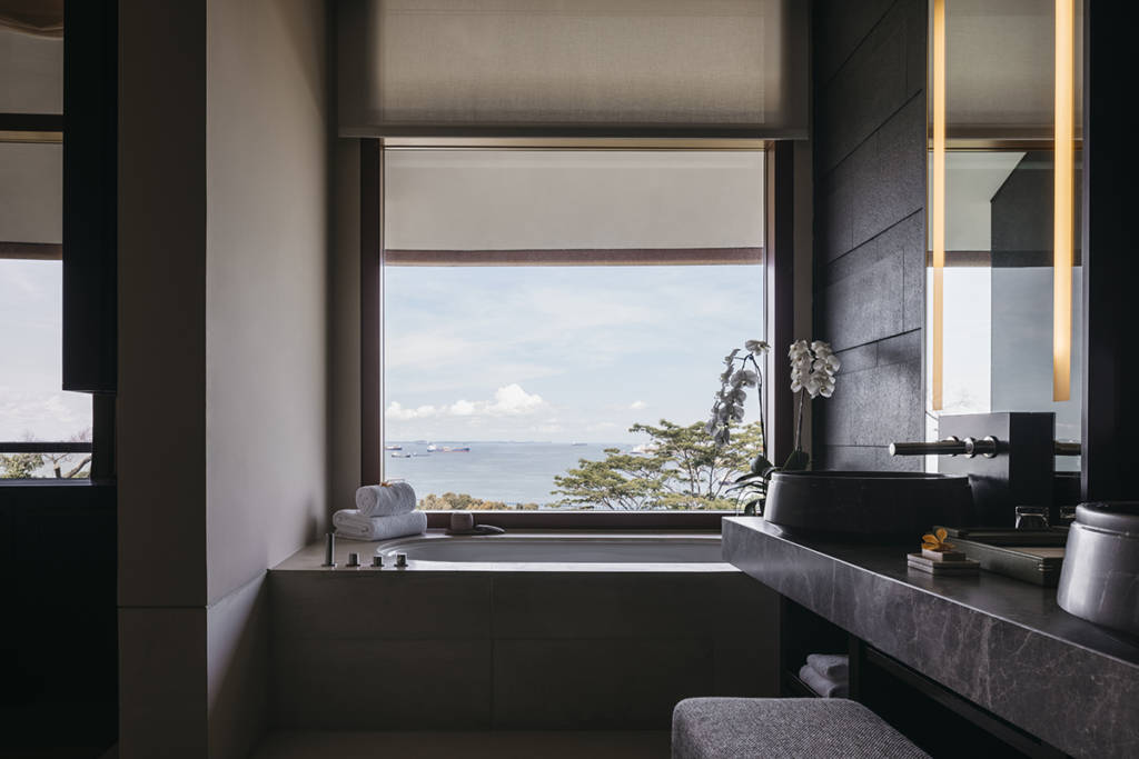 A bath by a window with a view of the sea