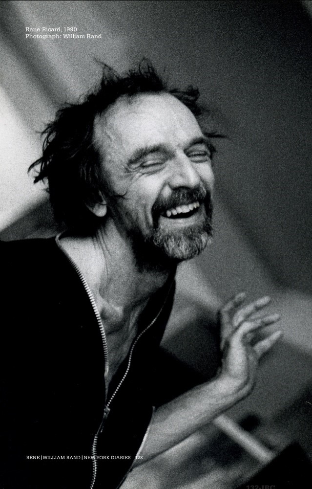 A man with a beard and black hair laughing with his eyes closed