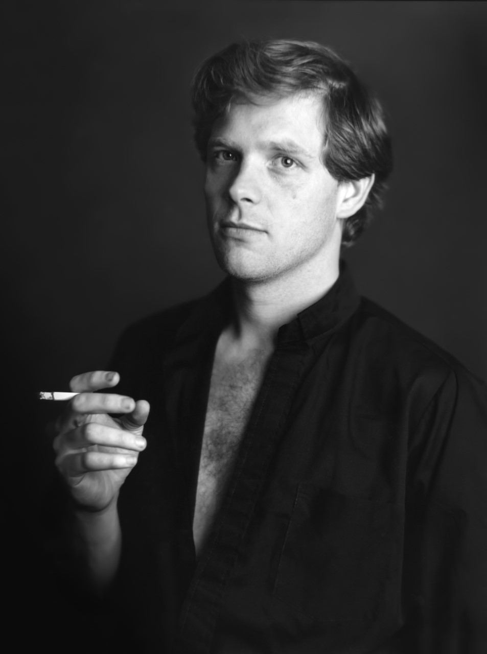 A man wearing a black shirt holding a cigarette
