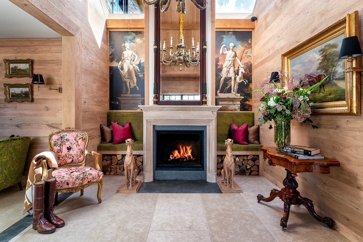 A fireplace with golden dog sculptures on each side and a pink chair