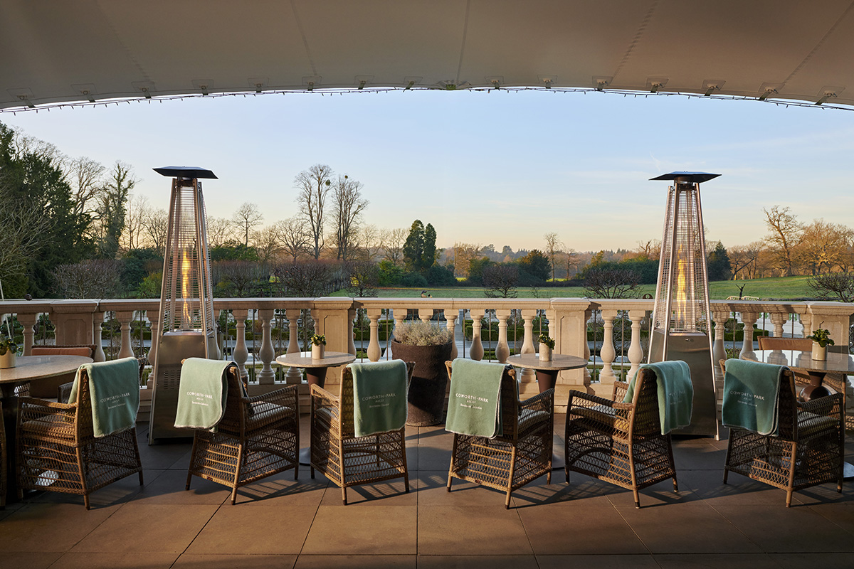 A terrace with green blankets on chairs and outdoor gas heaters