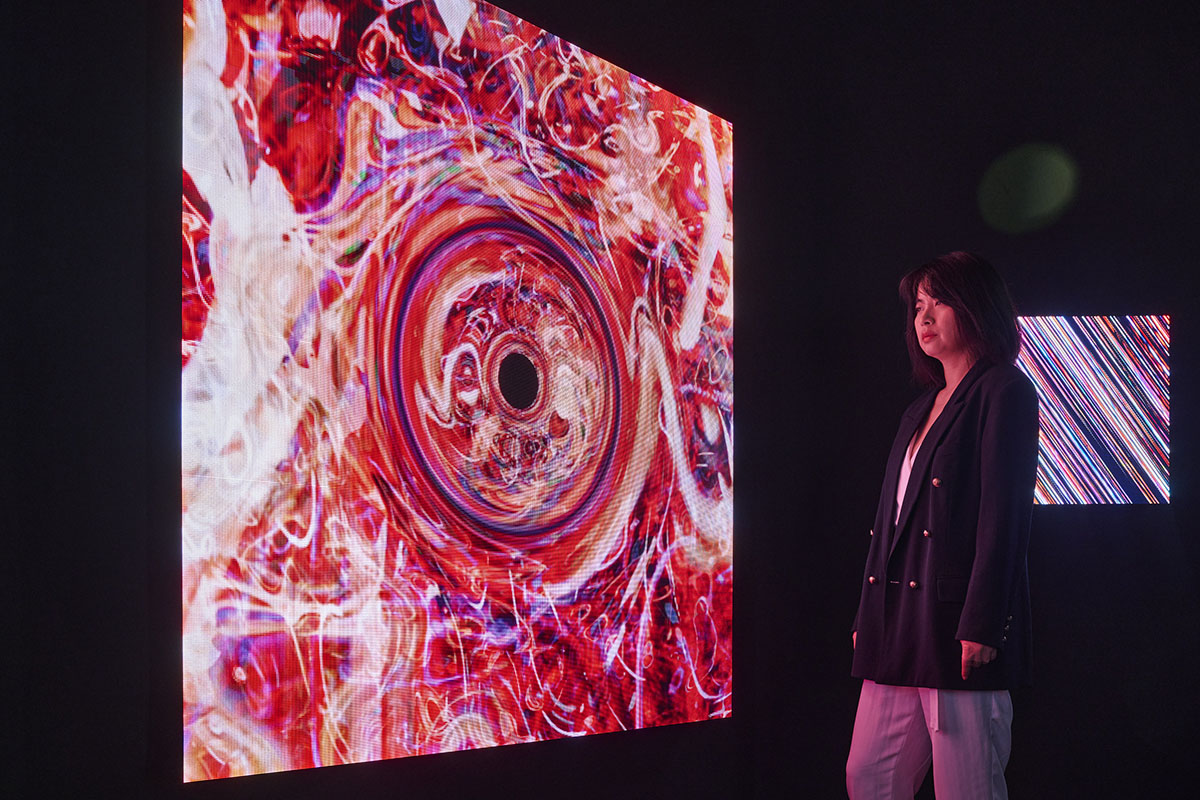 A woman looking at a red and pink light installation