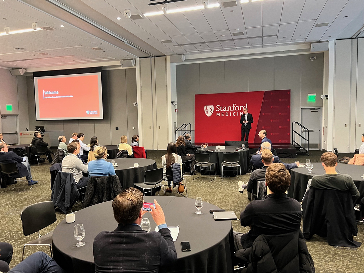 conference room with a red board and a man speaking on a stage