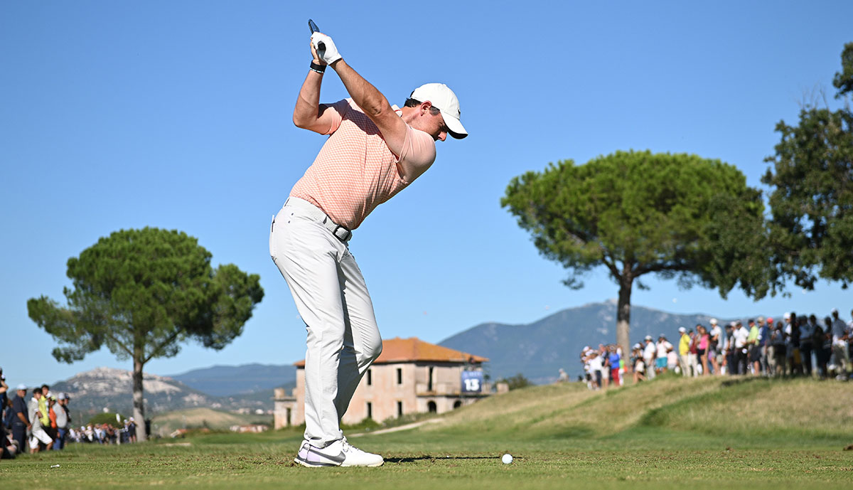 A man playing golf wearing a pink top and white trousers