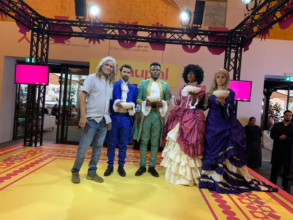 People in costumes standing on a stage holding bowls of food